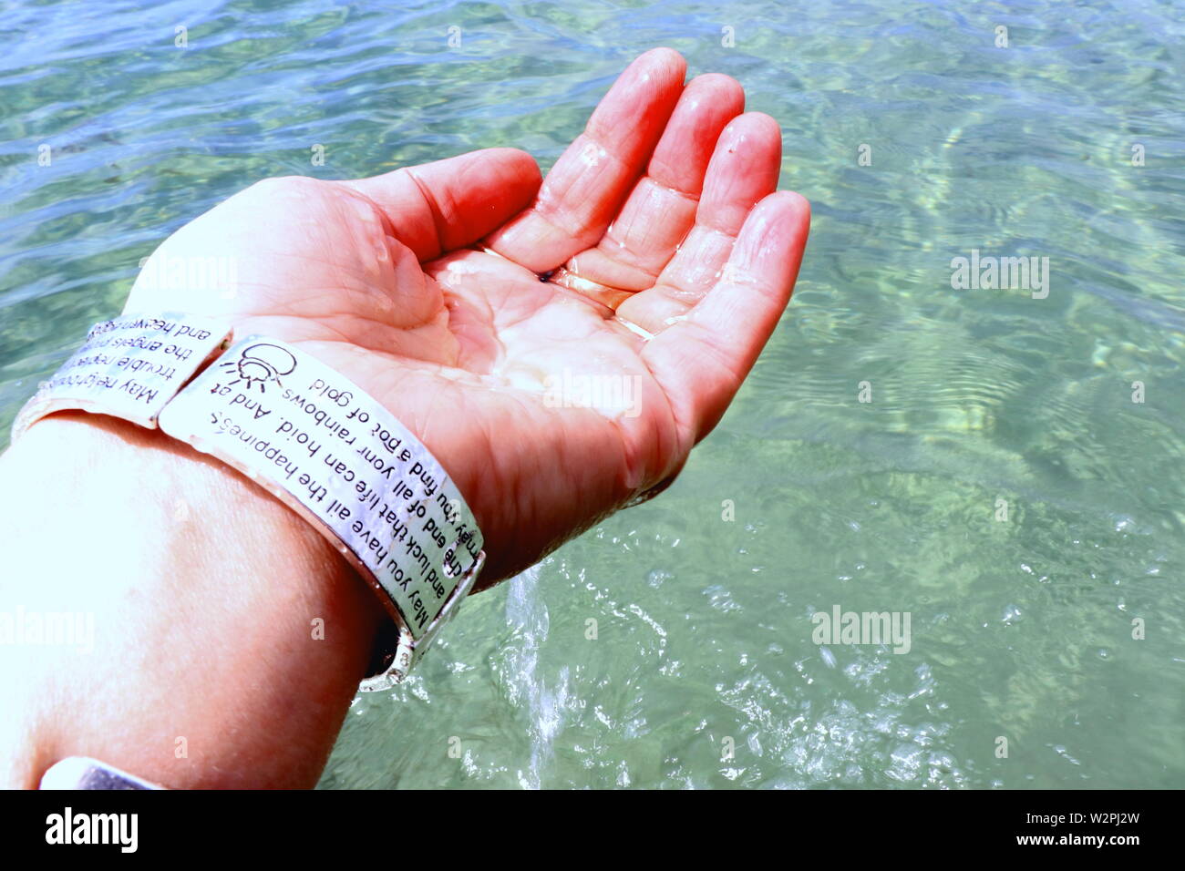 Woman's hand with silver bracelets et bagues, les projections dans l'eau de mer Banque D'Images
