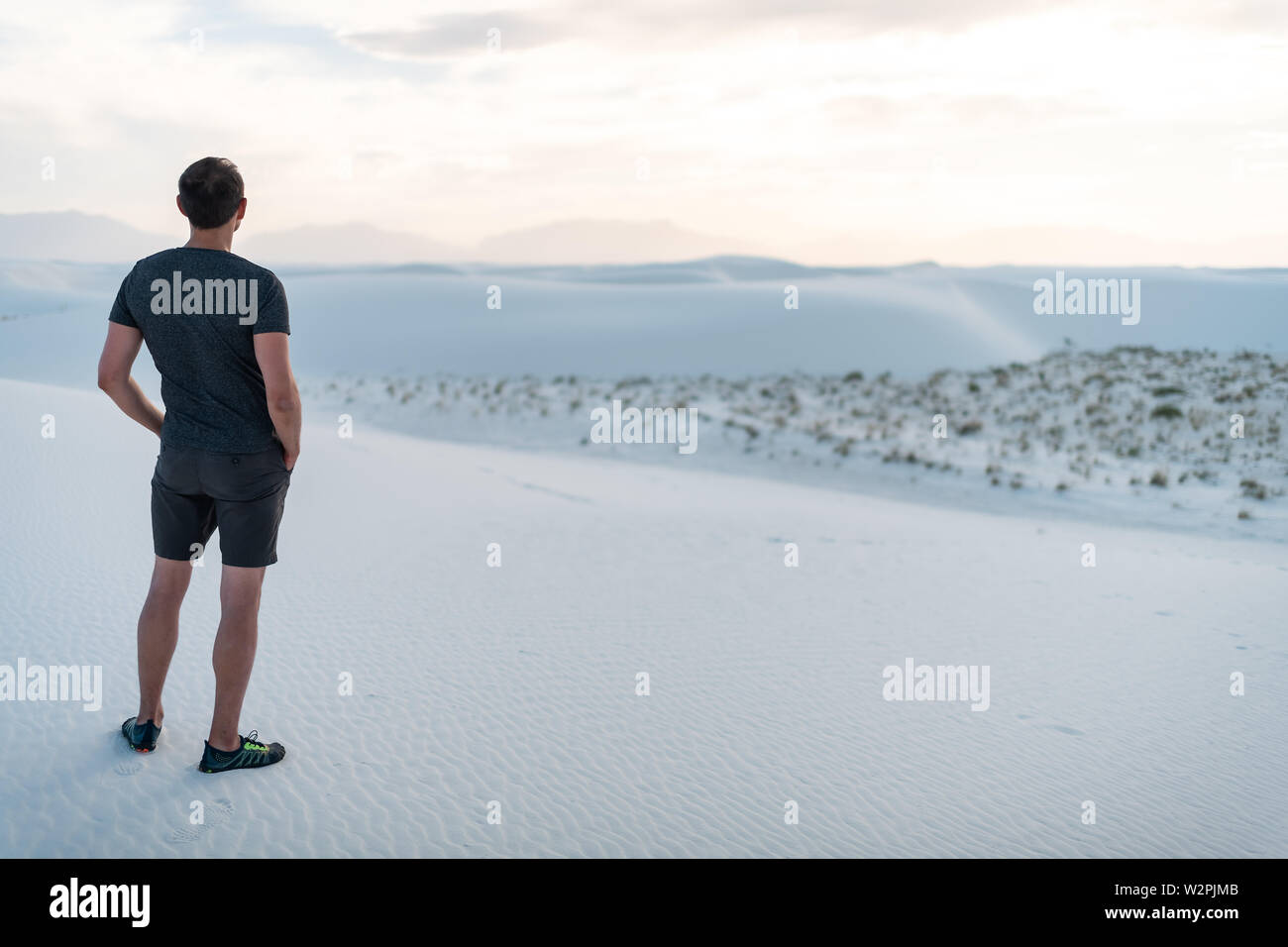 L'homme debout sur du sable dans les dunes de sable blanc national monument dans le Nouveau Mexique à l'horizon au coucher du soleil sur les montagnes et d'organes Banque D'Images