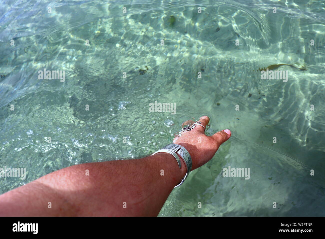 Woman's hand with silver bracelets et bagues, les projections dans l'eau de mer Banque D'Images