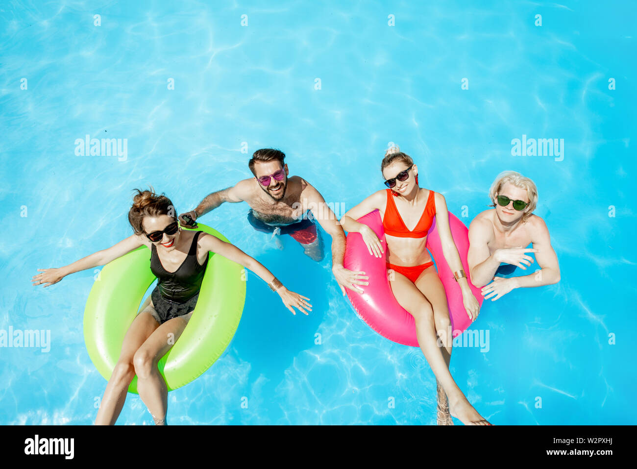 Un groupe d'amis heureux d'avoir l'amusement, la natation avec jouets gonflables dans la piscine en plein air, vue de dessus Banque D'Images