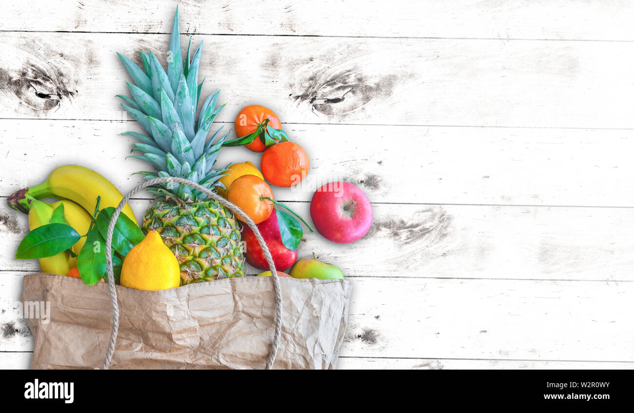 Vue de dessus du sac en papier rempli de fruits biologiques sains contre l'arrière-plan du tableau en bois blanc Banque D'Images