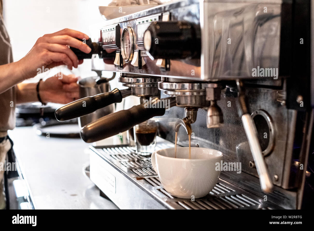 Close up de la personne proposant un cappuccino à l'aide de la machine à espresso commerciale. Banque D'Images