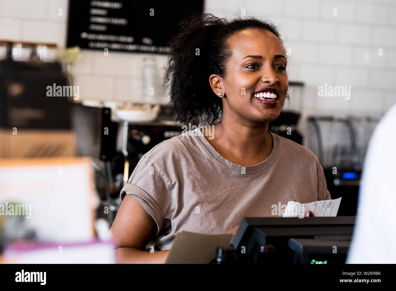 Une femme en souriant barista bienvenue près du compteur dans un café. Banque D'Images