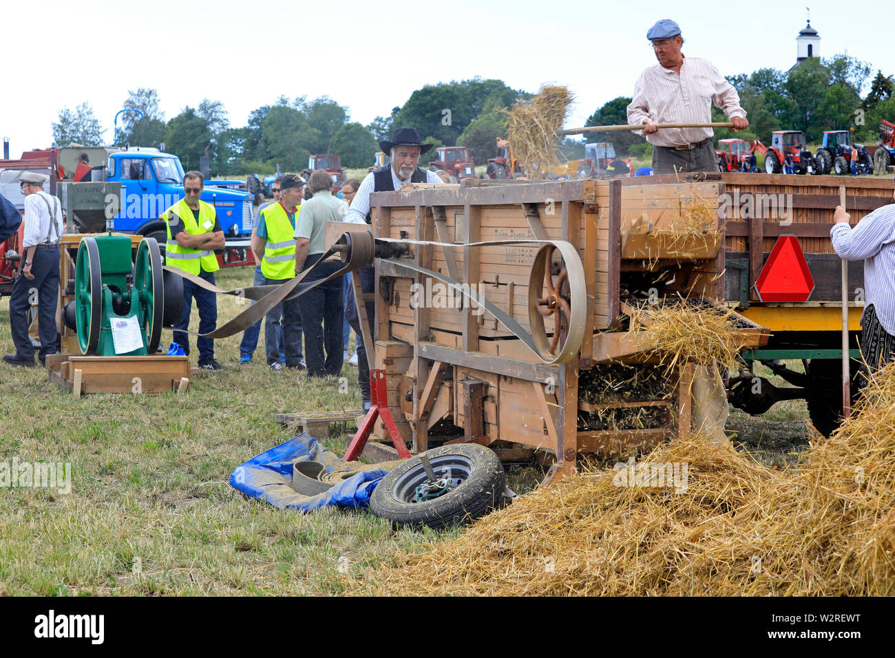 Kama & Mac Gregor, en Finlande. Le 6 juillet 2019. Les personnes travaillant avec Paavo année 1935 batteuse modèle exploité par John Deere Waterloo Boy K à l'arrêt moteur. Banque D'Images