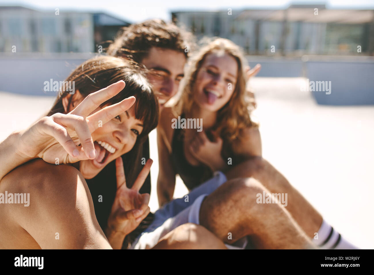 Prendre femme avec des amis selfies assis à l'extérieur. Cheerful friends faire un extérieur. selfies Banque D'Images