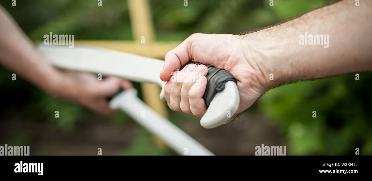L'Eskrima et wushu démontre l'instructeur technique de combat à la machette avec son élève. Long Couteau arme de la formation. Démonstration avec l'épée en plastique Banque D'Images