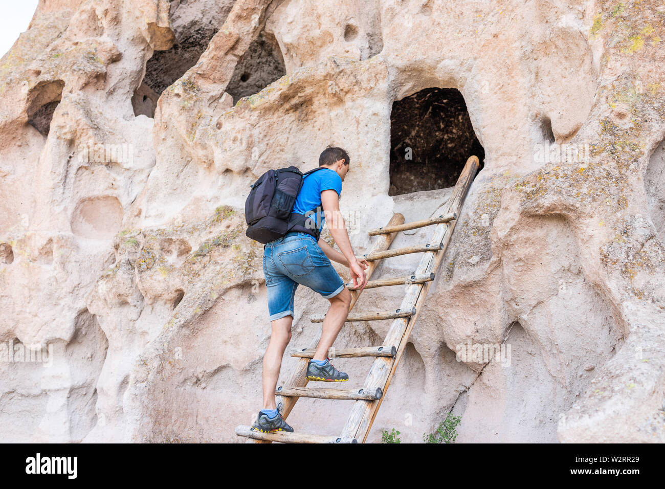 Man climbing ladder sur sentier en boucle principale en chemin Bandelier National Monument au Nouveau Mexique en été par canyon falaise Banque D'Images