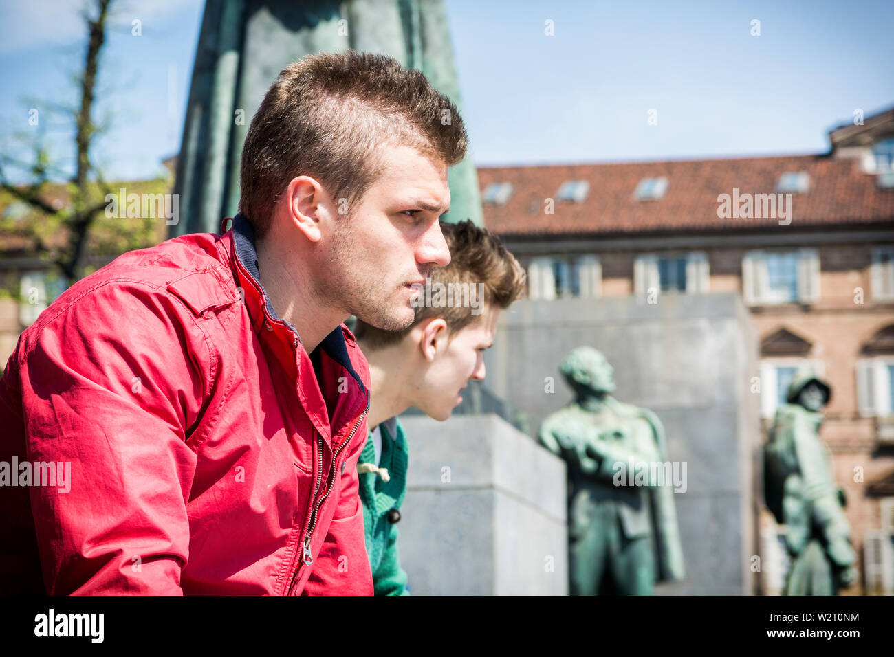 Deux jeunes hommes assis sur le mur inférieur en milieu urbain Banque D'Images