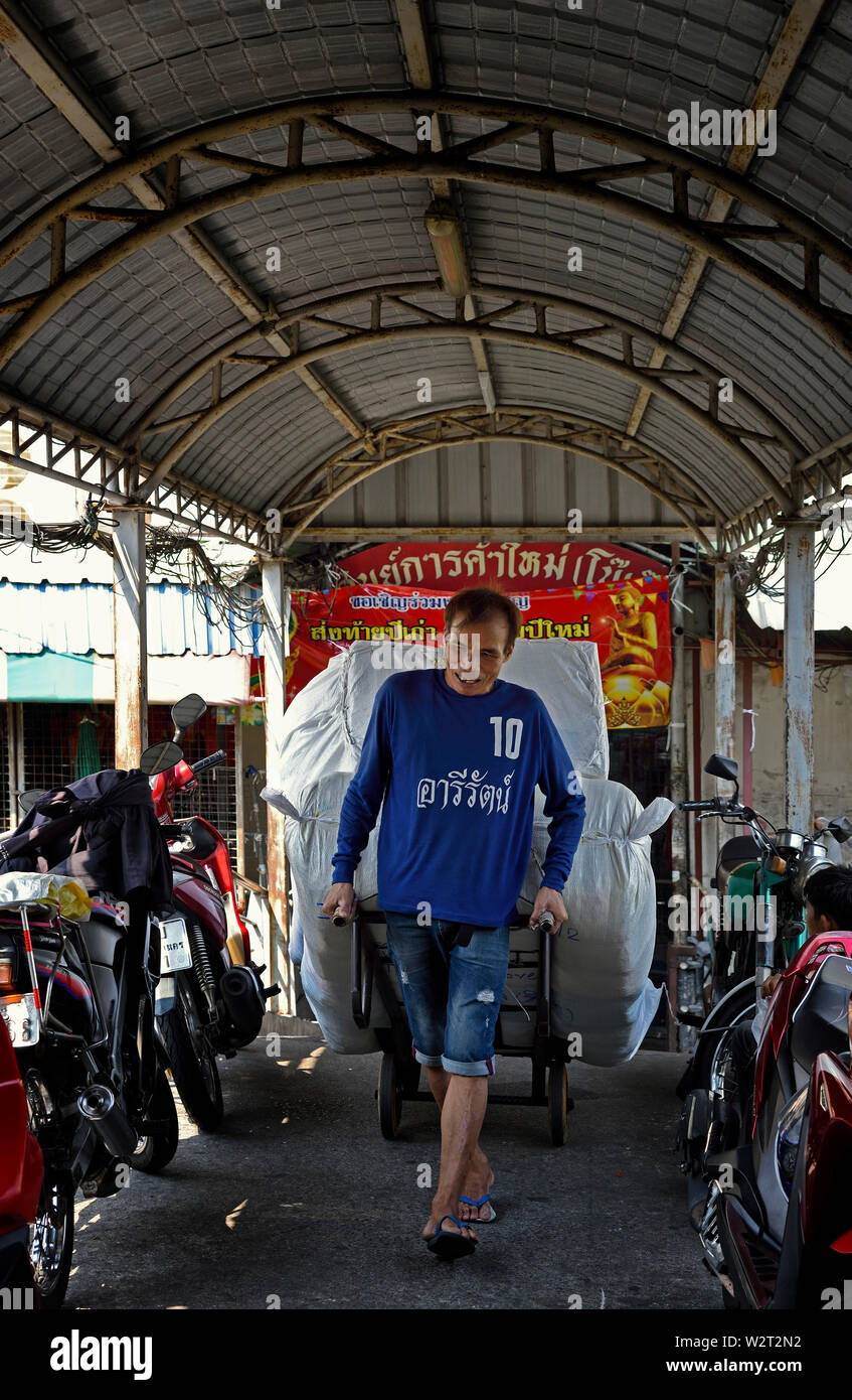Bangkok, Thaïlande - 15 février, 2019 : un homme tirant un lourd chariot chargé avec les textiles sur un pont-canal près de bobae market Banque D'Images
