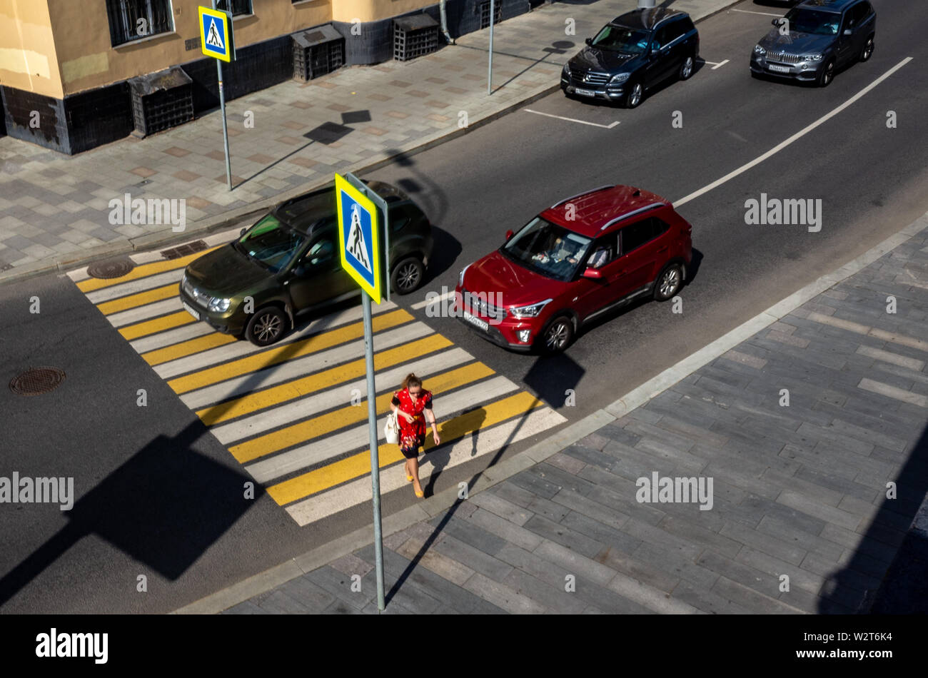 30 mai 2019, Moscou, Russie. La jeune fille en rouge traverse la rue à un passage pour piétons à Moscou. Banque D'Images