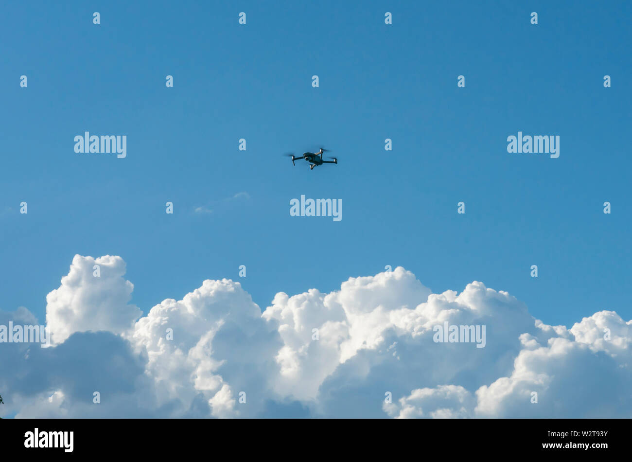 L'quadcopter a plané au-dessus des nuages contre le ciel bleu Banque D'Images