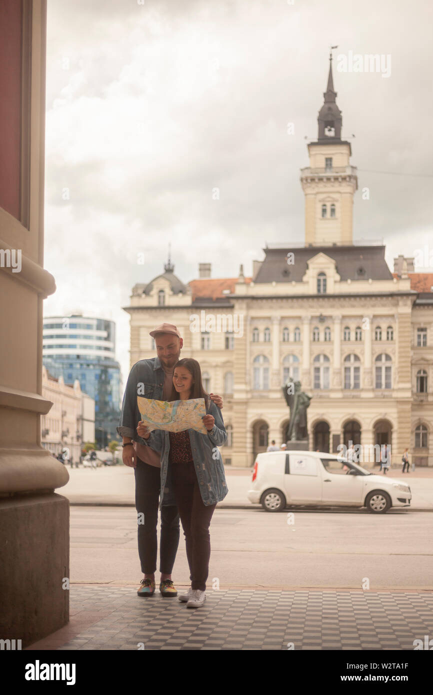 Deux jeunes gens, amis ou en couple, à la recherche d'un plan de ville ensemble. Vieille ville européenne square architecture. Banque D'Images