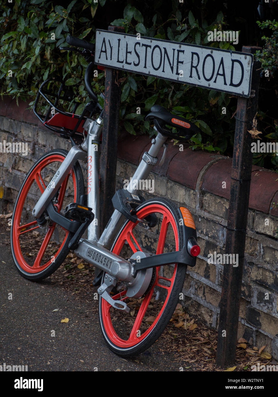 Cambridge, Angleterre, Royaume-Uni - Un mobike voitures abandonnées de vélo et appuyé contre une plaque de rue Banque D'Images