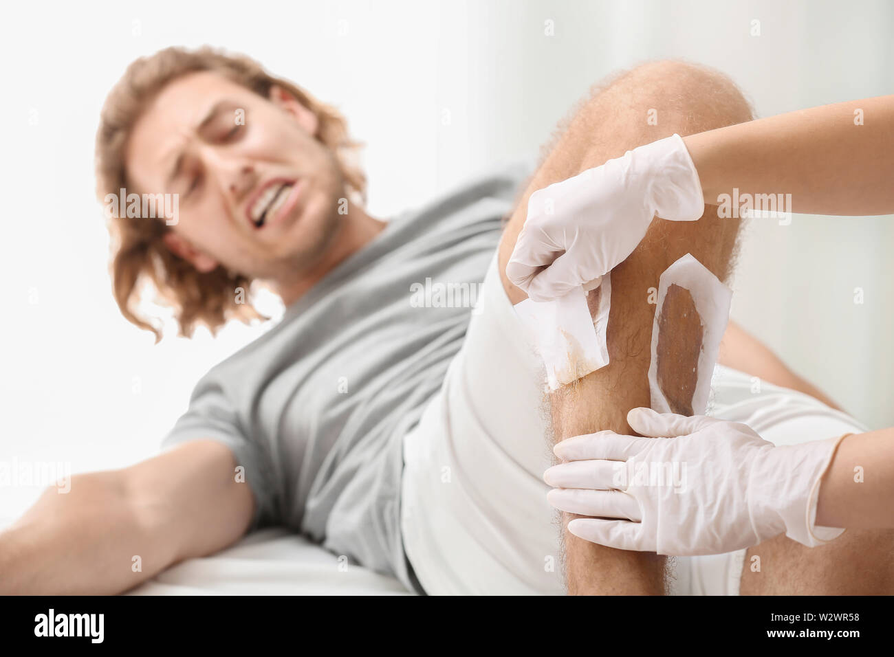 Homme souffrant de douleur pendant l'épilation à la cire des jambes dans  salon de beauté Photo Stock - Alamy