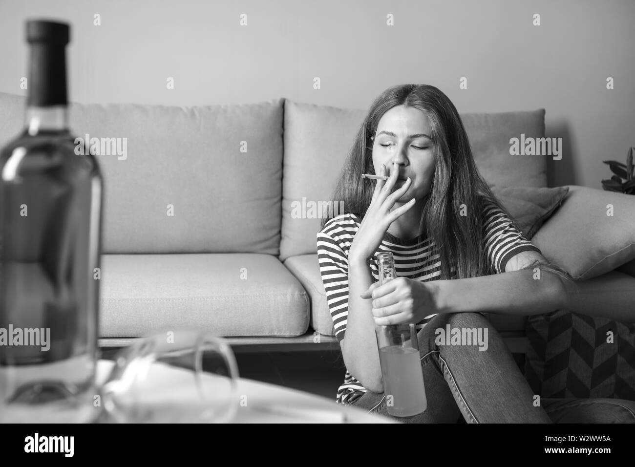 Jeune femme avec la dépendance à l'alcool et les cigarettes à la maison Banque D'Images