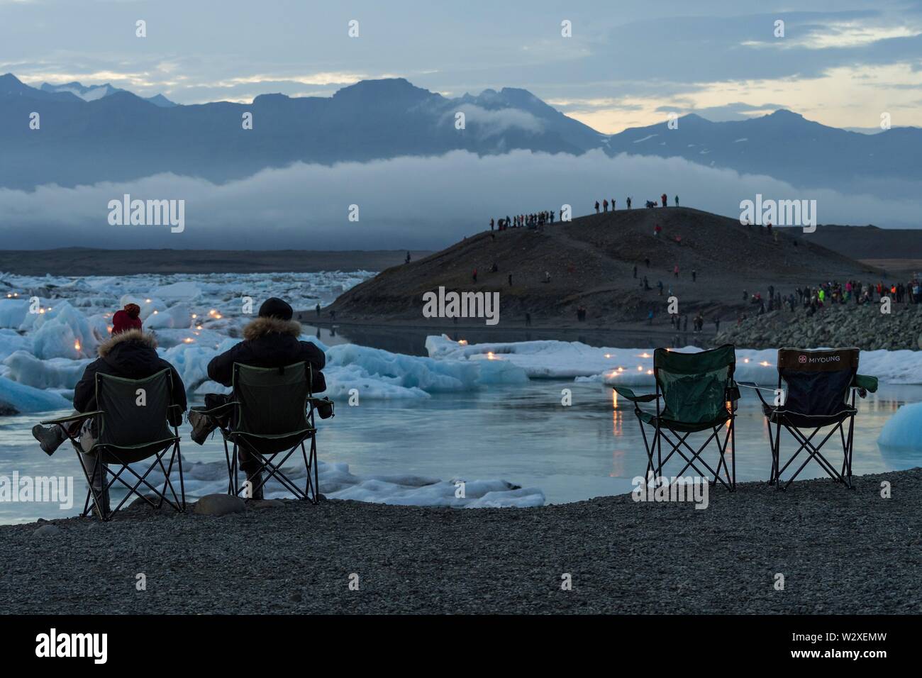 Les touristes en chaises de camping en attente d'artifice à la lagune glaciaire Jokulsarlon, le tourisme de masse, le sud de l'Islande, Islande Banque D'Images