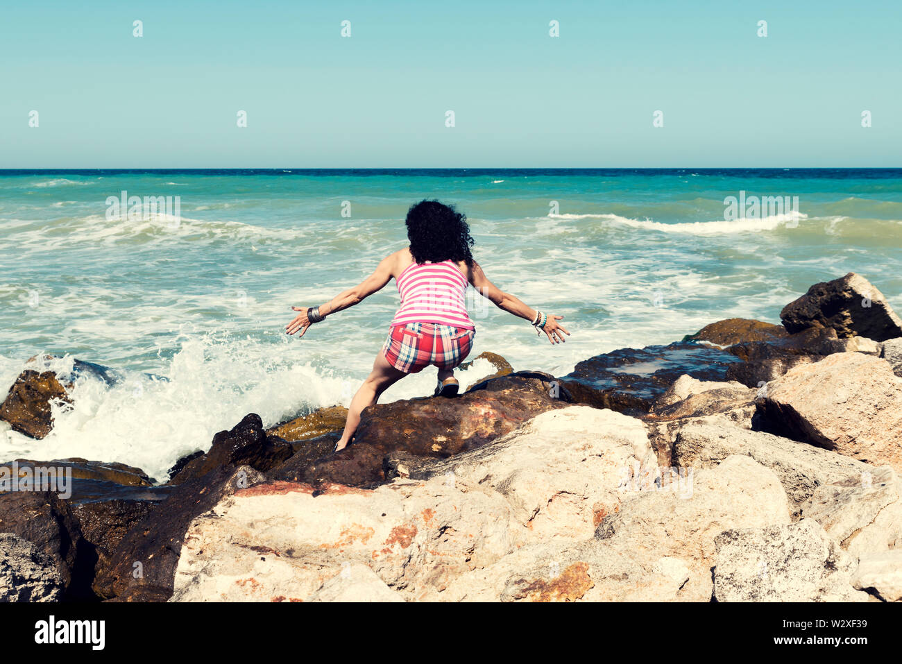 Jeune femme accroupie sur une plage de la mer profiter du beau temps ensoleillé Selective focus Banque D'Images