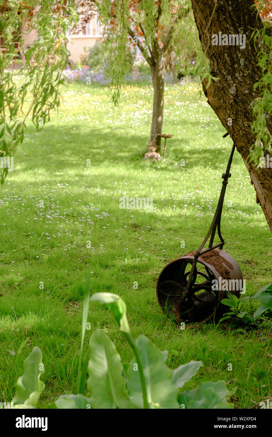 Rouleau de jardin en fonte Vintage appuyé contre un arbre Banque D'Images