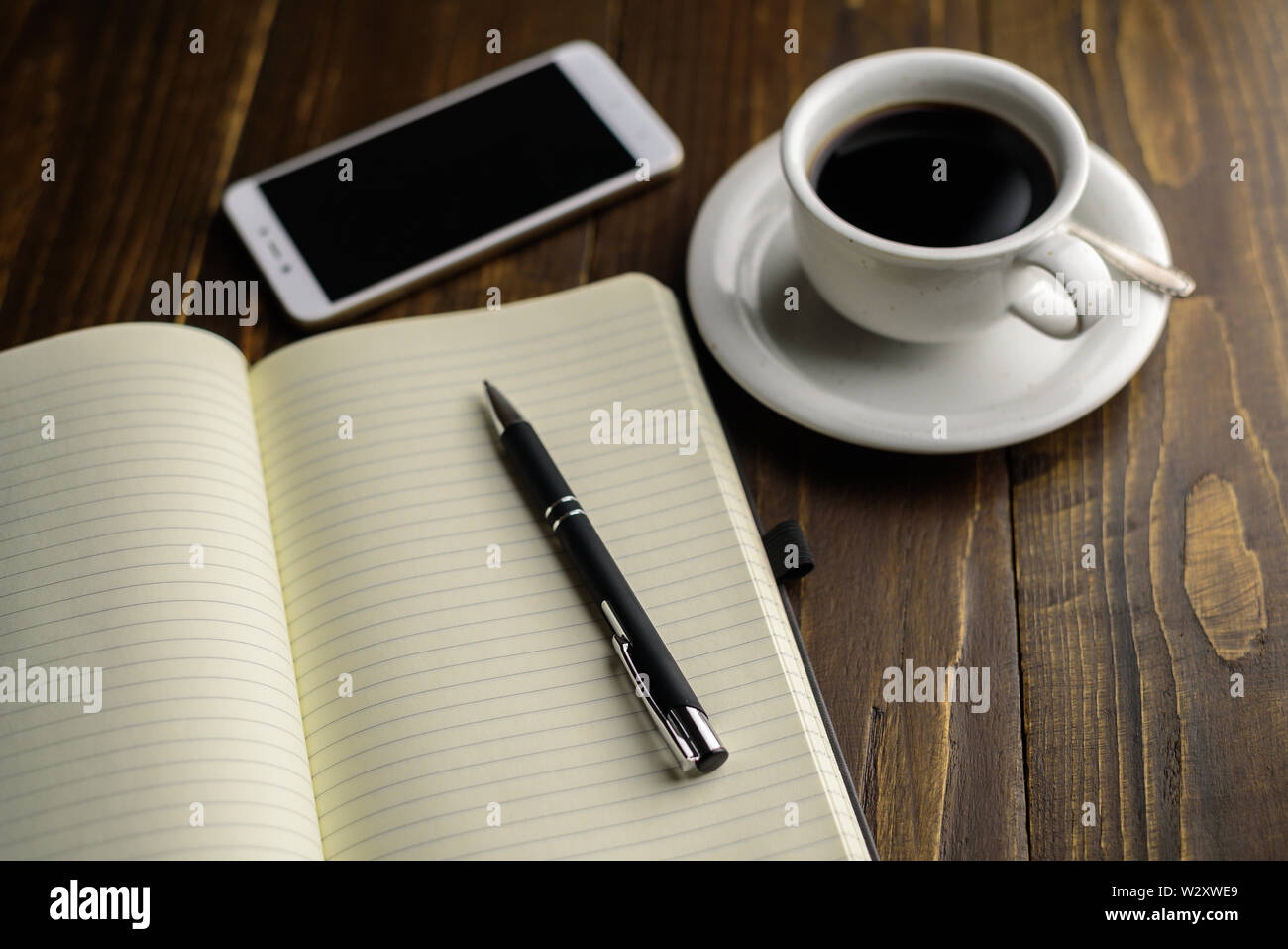 Café noir, stylo et ordinateur portable sur une table en bois sombre. Lieu de travail Banque D'Images