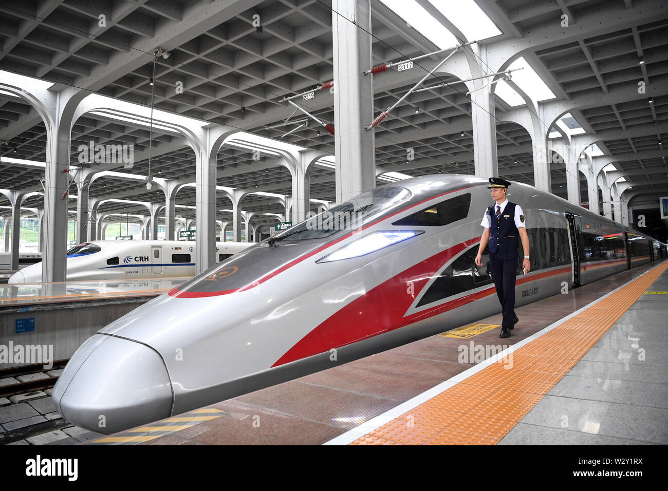 (190711) -- CHONGQING, 11 juillet 2019 (Xinhua) -- un membre du personnel de chemin de fer passe devant le train G319 à la gare de l'ouest de Chongqing dans le sud-ouest de la Chine, Chongqing, le 11 juillet 2019. Le bullet train G319 a quitté la gare de l'ouest de Chongqing à 8 h 20 et arrivera à Hong Kong West Kowloon Station autour de 7,5 heures plus tard. Un siège de seconde classe pour les 7,5 heures de voiture coûte 660 yuans (environ 96 dollars américains). (Xinhua/Tang Yi) Banque D'Images