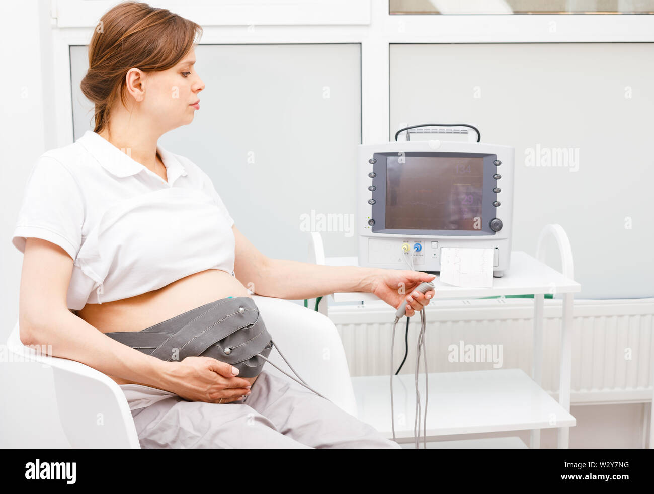 Pregnant woman sitting dans cardiotocography clinique effectuant (CTG). La courroie sur son ventre relié à l'Cardiotocograph alias machine Feta électronique Banque D'Images