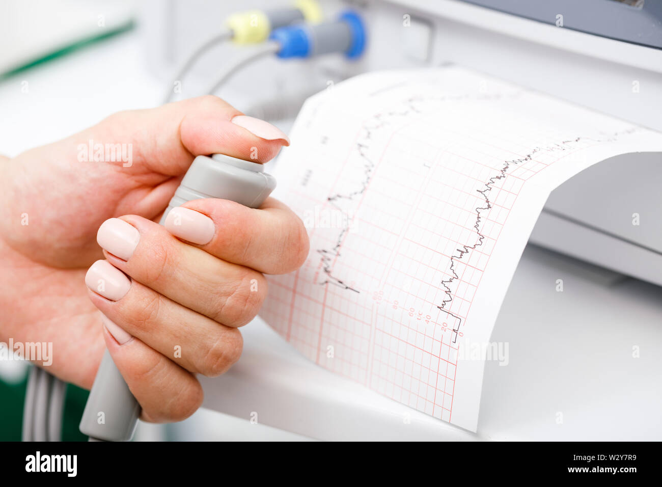 Close-up shot of pregnant woman's hand holding contrôleur de l'Cardiotocograph alias machine de monitorage électronique du foetus (EFM) enregistrement de la fetal heartb Banque D'Images