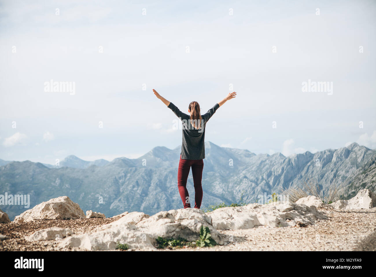 Fille au sommet d'une montagne ou une colline lève les mains vers le haut. Elle est heureuse et libre. Banque D'Images