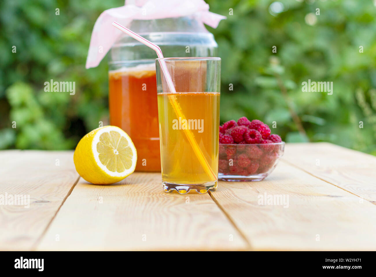 Kombucha avec bol en verre, verre coulé avec Kombucha et les framboises dans le jardin d'été. Banque D'Images