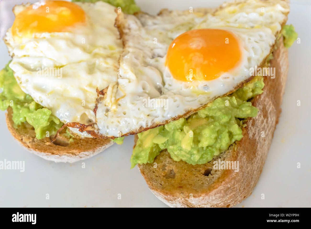 Deux œufs frits sur la purée d'avocat sur pain complet d'épaisseur Banque D'Images
