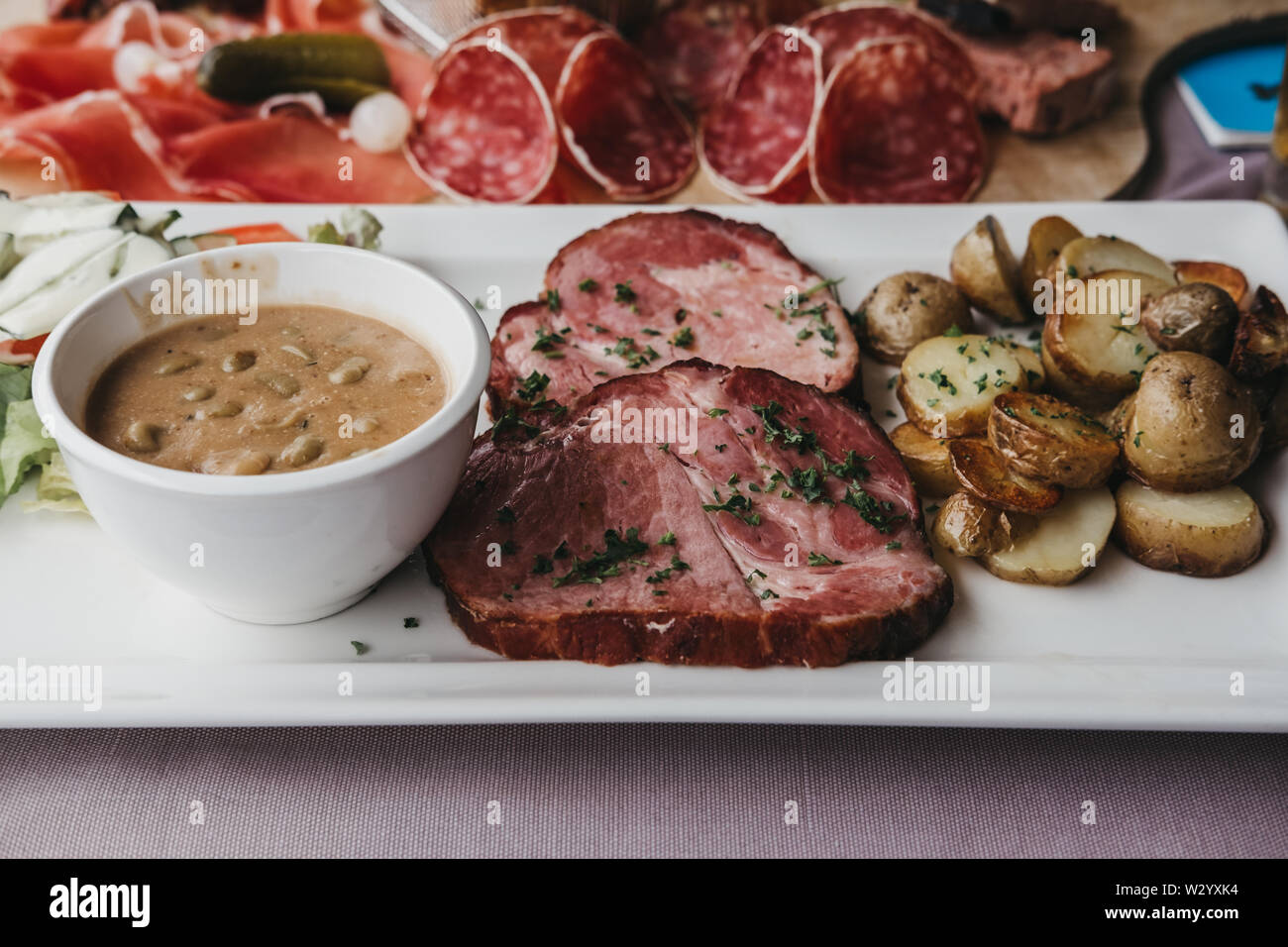 Le Luxembourgeois traditionnels lave Judd mat Gaardebounen, collier fumé de porc aux fèves, sur une plaque à côté de plateau de viande froide, selective focus. Banque D'Images