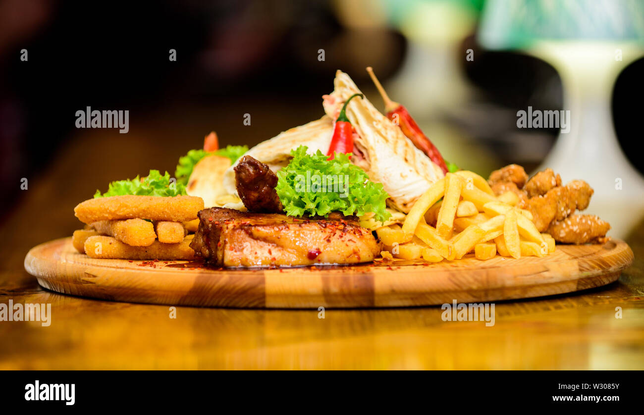 Les repas au restaurant. Planche de bois avec beaucoup de frites et bâtonnets de poisson viande burrito steak servi avec une salade. Menu snack-bar. Calories élevé pour le groupe d'amis. De délicieux en-cas savoureux. Snack pour la bière. Banque D'Images