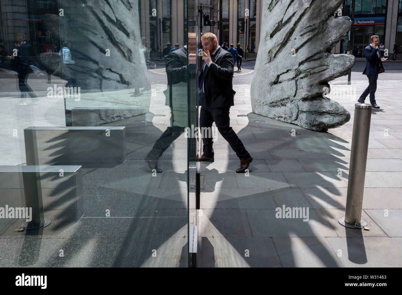 Un homme d'affaires de l'industrie financière passe devant la sculpture intitulée City Wing sur Threadneedle Street dans la ville de Londres, le quartier financier de la capitale (aka le Square Mile), le 11 juillet 2019, à Londres, en Angleterre. L'aile est de la ville par l'artiste Christopher Le Brun. Les dix mètres de haut est la sculpture en bronze par le président de la Royal Academy of Arts, Christopher Le Brun, commandé par Hammerson en 2009. Elle est appelée 'La Ville' de l'aile et a été jeté par Morris Singer, fondateurs de l'art réputé pour être la plus ancienne fonderie d'art dans le monde. Banque D'Images