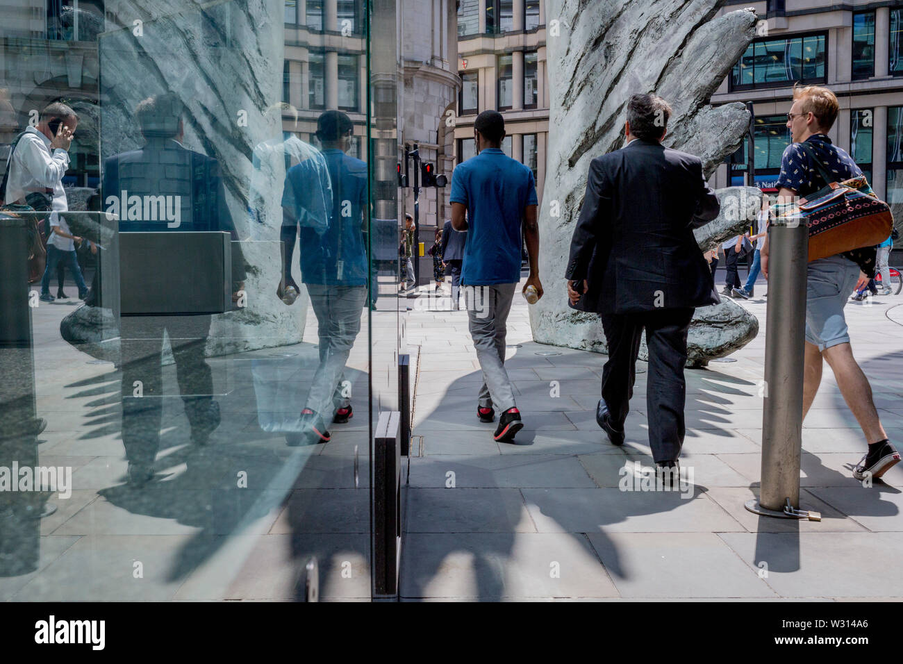 Les hommes d'affaires de l'industrie financière à pied au-delà de la sculpture intitulée City Wing sur Threadneedle Street dans la ville de Londres, le quartier financier de la capitale (aka le Square Mile), le 11 juillet 2019, à Londres, en Angleterre. L'aile est de la ville par l'artiste Christopher Le Brun. Les dix mètres de haut est la sculpture en bronze par le président de la Royal Academy of Arts, Christopher Le Brun, commandé par Hammerson en 2009. Elle est appelée 'La Ville' de l'aile et a été jeté par Morris Singer, fondateurs de l'art réputé pour être la plus ancienne fonderie d'art dans le monde. Banque D'Images