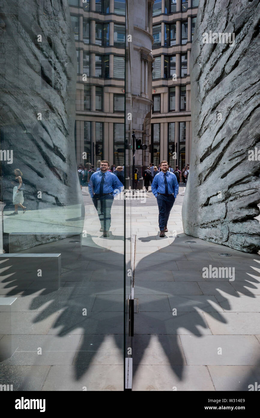 Les hommes d'affaires de l'industrie financière à pied au-delà de la sculpture intitulée City Wing sur Threadneedle Street dans la ville de Londres, le quartier financier de la capitale (aka le Square Mile), le 11 juillet 2019, à Londres, en Angleterre. L'aile est de la ville par l'artiste Christopher Le Brun. Les dix mètres de haut est la sculpture en bronze par le président de la Royal Academy of Arts, Christopher Le Brun, commandé par Hammerson en 2009. Elle est appelée 'La Ville' de l'aile et a été jeté par Morris Singer, fondateurs de l'art réputé pour être la plus ancienne fonderie d'art dans le monde. Banque D'Images