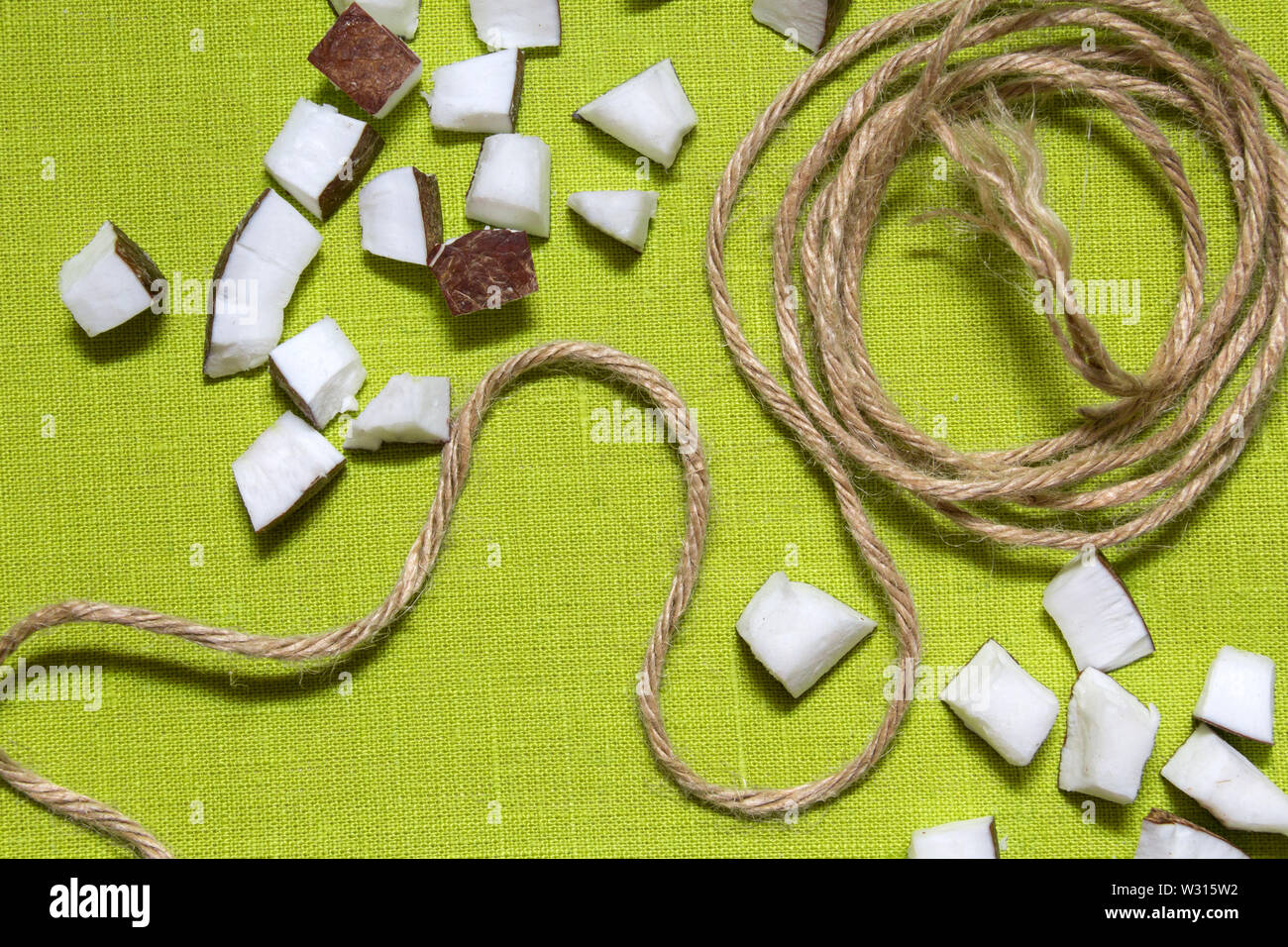 Morceaux de noix de coco et corde de jute sur fond vert. Banque D'Images