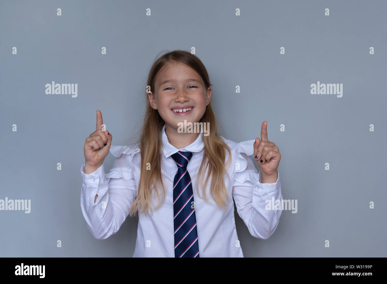 Les jeunes écoliers pointant vers le haut, portrait. Preteen lycéenne looking at camera, gesticulant au plafond. Happy girl, gamin dans l'uniforme scolaire. Retour à l'école, Banque D'Images