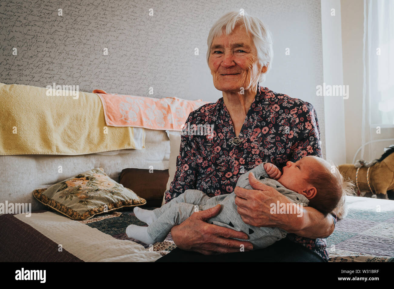 Grand-mère tient son arrière-petite-fille et ressemble à l'appareil photo Banque D'Images