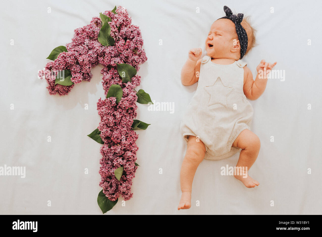 Télévision jeter la photo d'un bébé de 1 mois avec plusieurs faits de feuilles de chêne et de fleurs lilas Banque D'Images