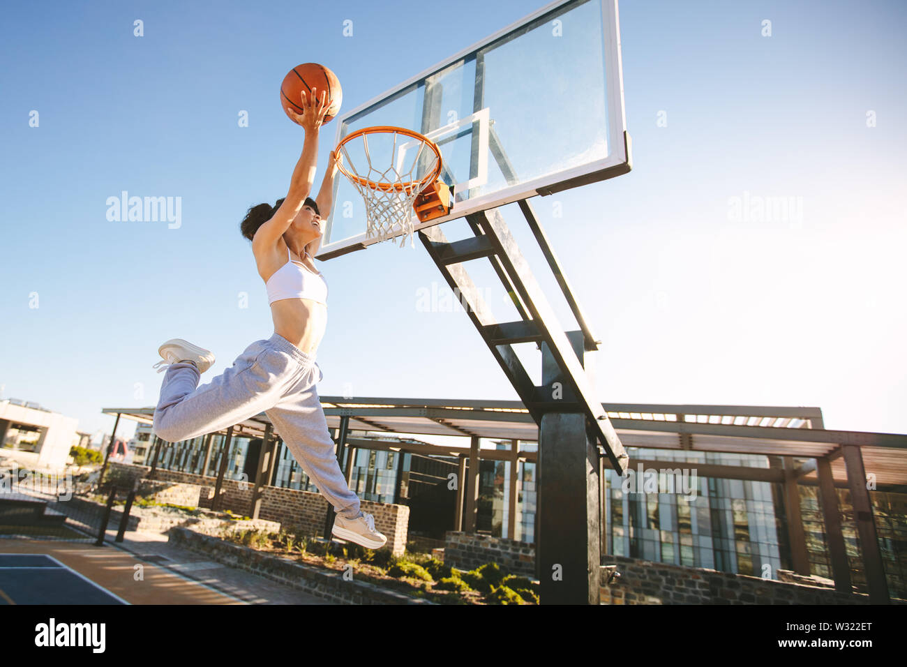 Joueur de basket-ball femme slam dunk sur cour de la rue. Jouer au basket-ball  féminin à l'extérieur sur journée d'été Photo Stock - Alamy