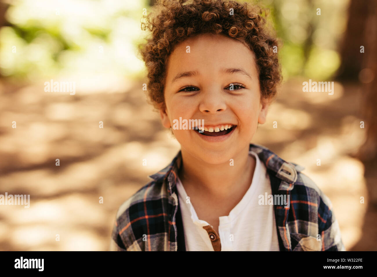 Close up portrait of cute boy smiling outdoors. Kid looking at camera et rire. Banque D'Images