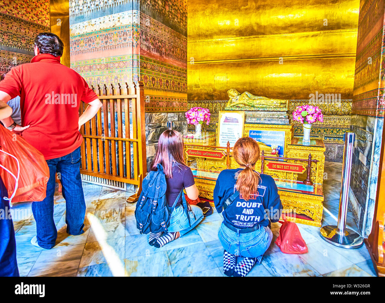 BANGKOK, THAÏLANDE - 22 avril 2019 : Deux jeunes filles assis sur les genoux et prier sur le petit autel du Bouddha couché dans Phranorn Viharn sanctuaire de Wat Pho te Banque D'Images