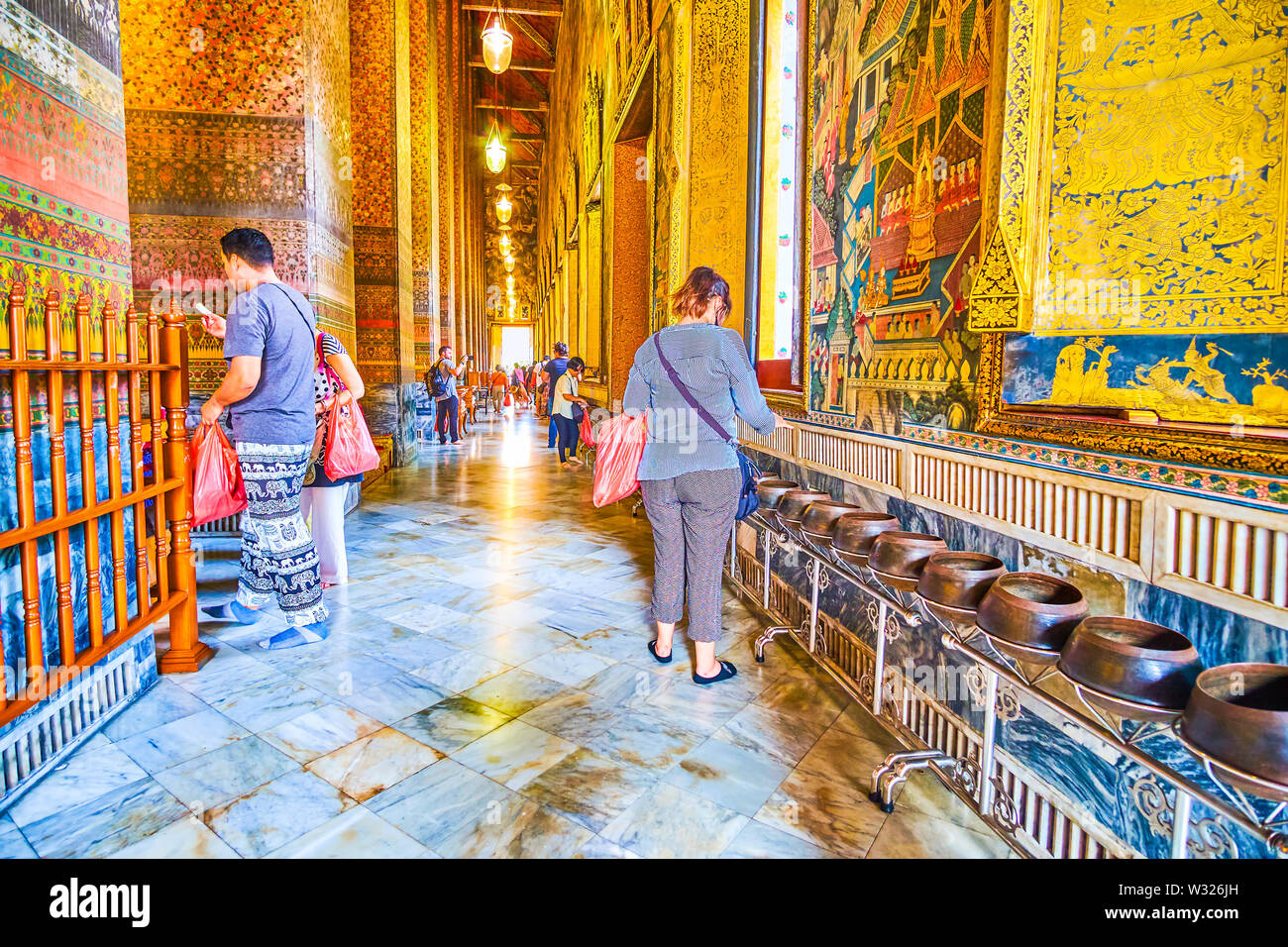 BANGKOK, THAÏLANDE - 22 avril 2019 : les touristes drop les pièces dans une gamme spéciale de bols, le rituel populaire pour attirer la bonne chance, temple Wat Pho Banque D'Images