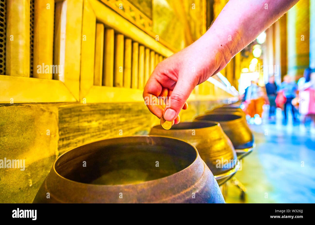 BANGKOK, THAÏLANDE - 22 avril 2019 : Le rituel de l'abandon de la pièce dans un bol en bronze, qui peuvent apporter une bonne fortune, au complexe du temple de Wat Pho, de l'Ap Banque D'Images