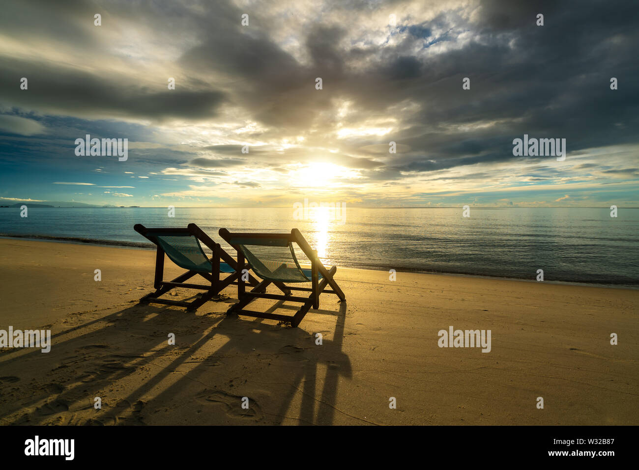 Deux chaises longues sur la plage au coucher du soleil avec une mer tropicale arrière-plan. Voyages et vacances dans l'été en mer. Banque D'Images