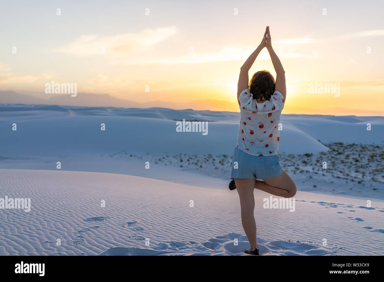 Fille femme retour l'exercice en équilibre sur une jambe à White Sands dunes national monument à Nouveau Mexique vue sur le coucher du soleil Banque D'Images