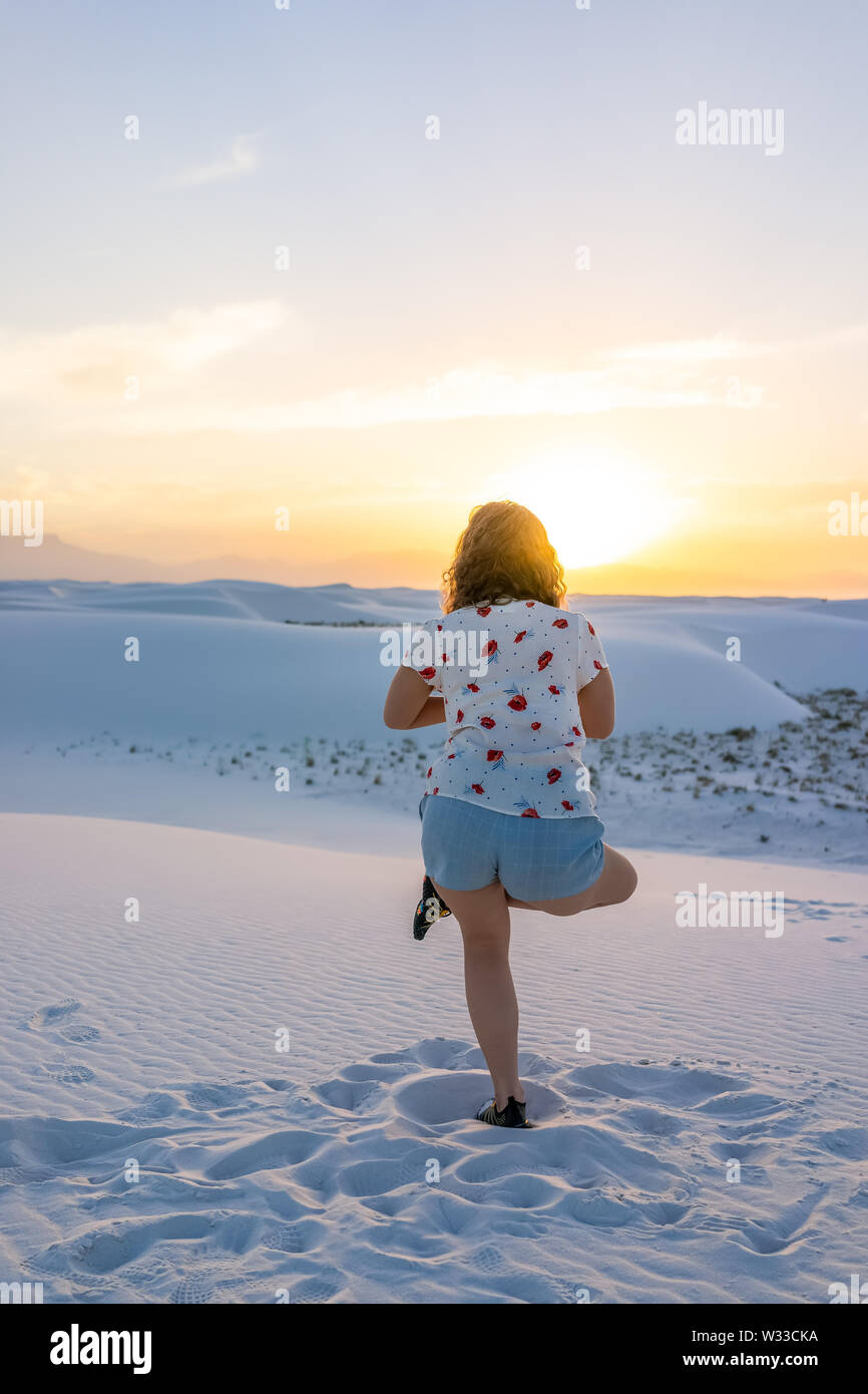 Retour femme exerçant en équilibre sur une jambe à White Sands dunes national monument à Nouveau Mexique vue sur le coucher du soleil Banque D'Images