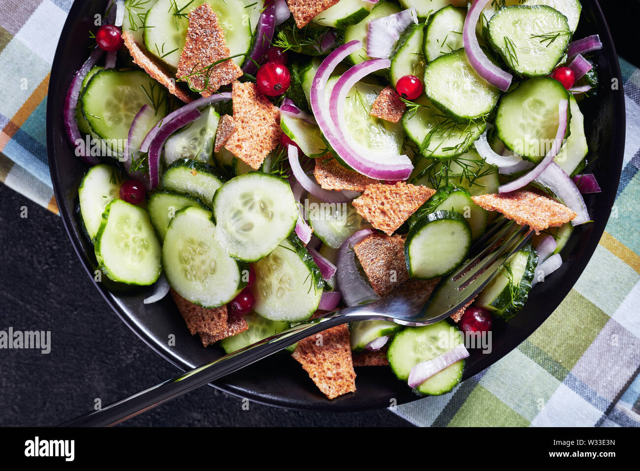 Close-up d'une partie de l'été délicieux salade de concombre, de groseille rouge, oignon rouge mariné et Crisp, tous faits de morceaux dans un bol noir, flatlay, mac Banque D'Images