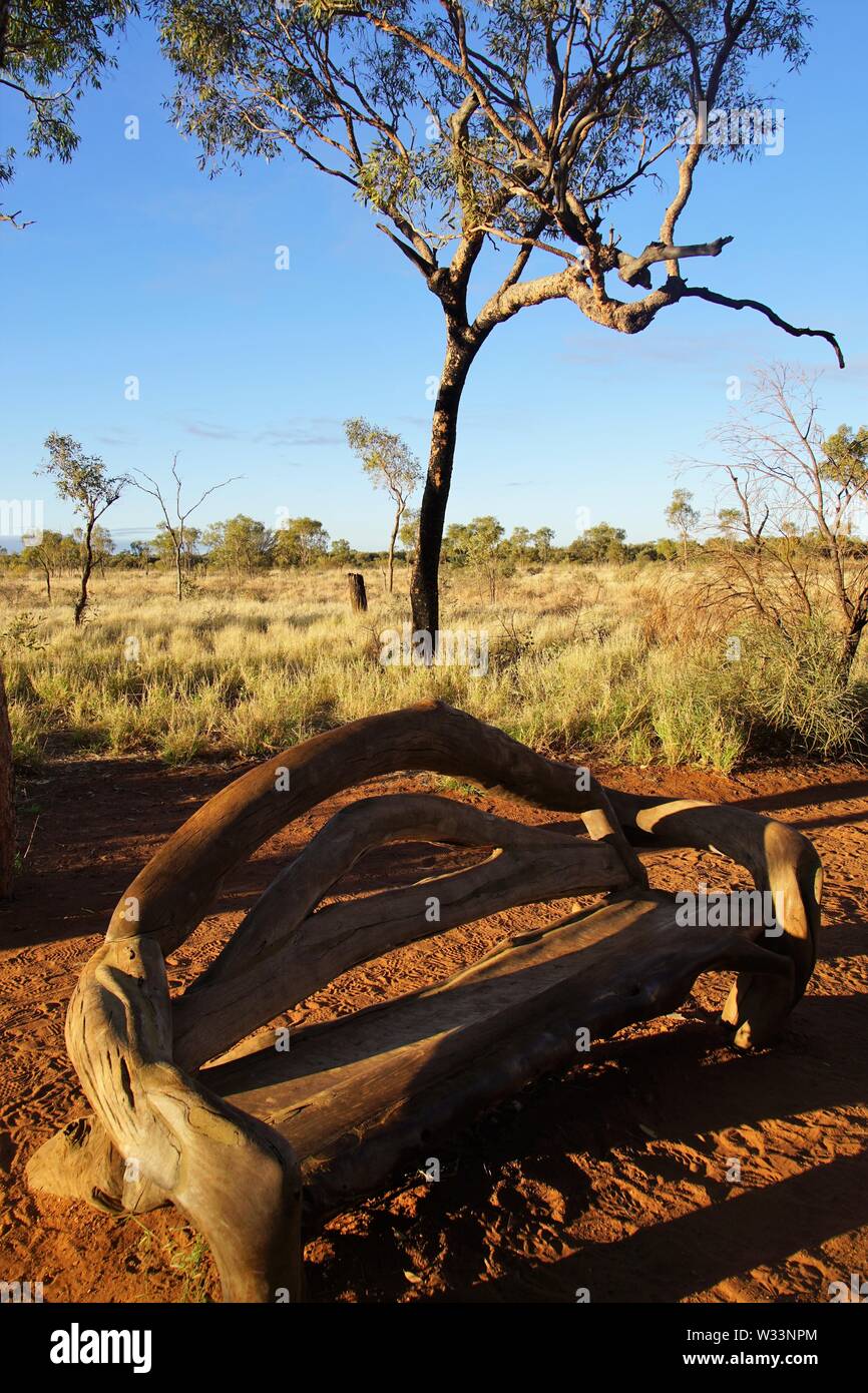 Banc en bois rustique sur la base d'Uluru à pied contre un paysage de désert ensoleillé Banque D'Images