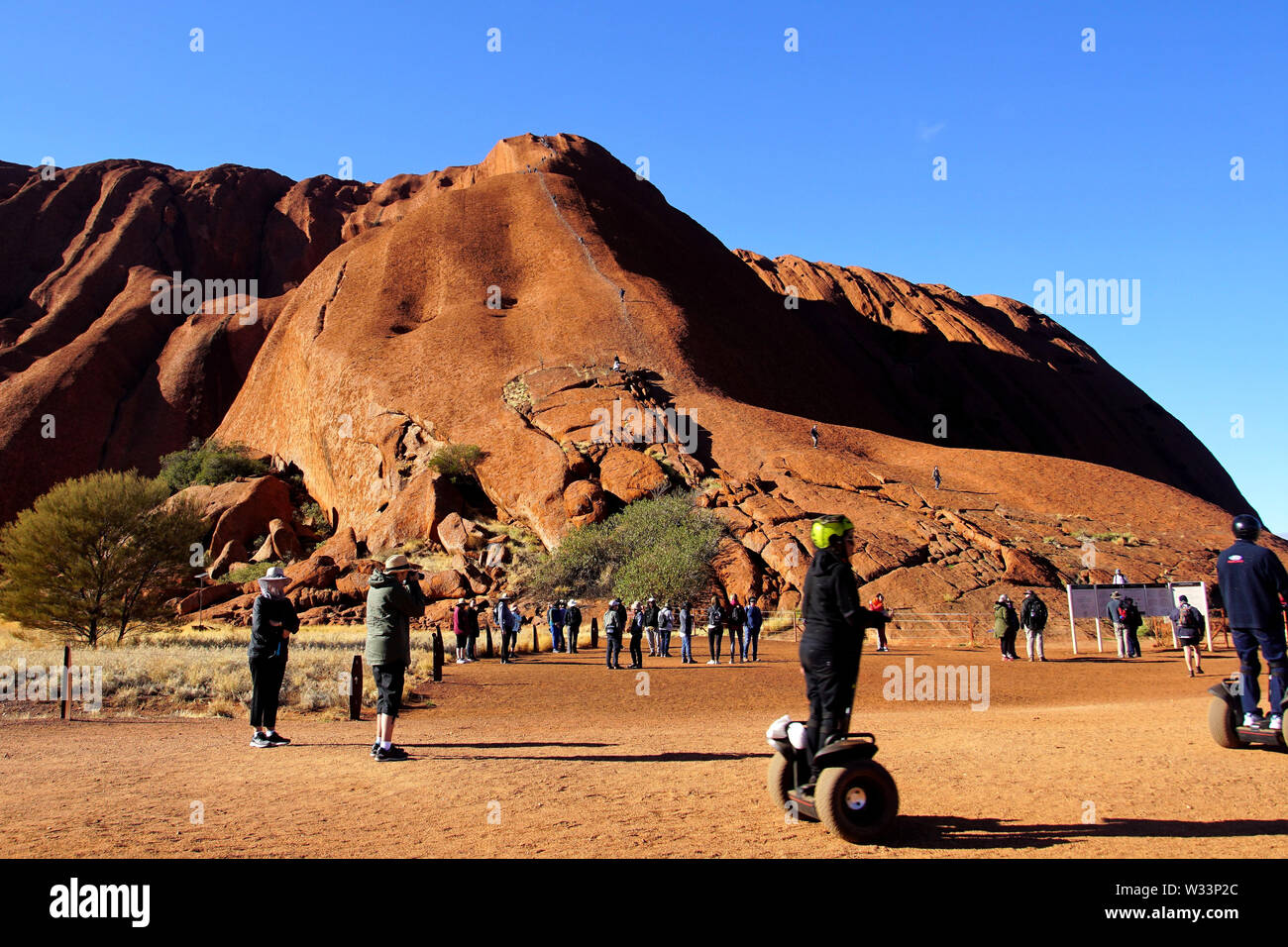 Les gens à l'Uluru grimper sur un matin d'hiver ensoleillé Banque D'Images