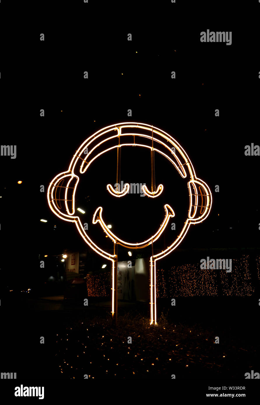 Vertical image of happy smiling face en néon sur le côté de la rue la nuit Banque D'Images
